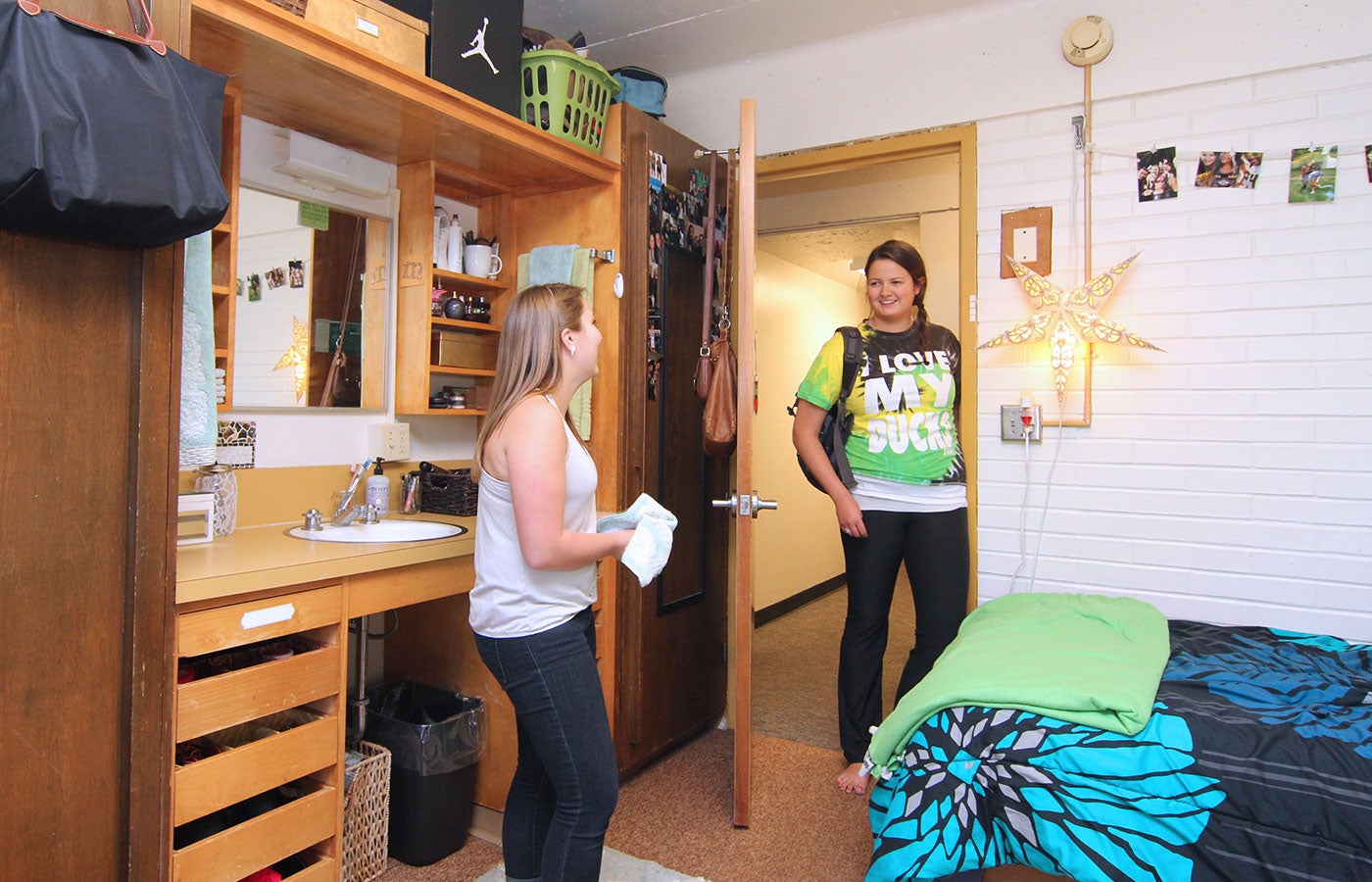 Make new friends in the residence halls. A student stands in the doorway of another students residence hall room and they are happily talking.